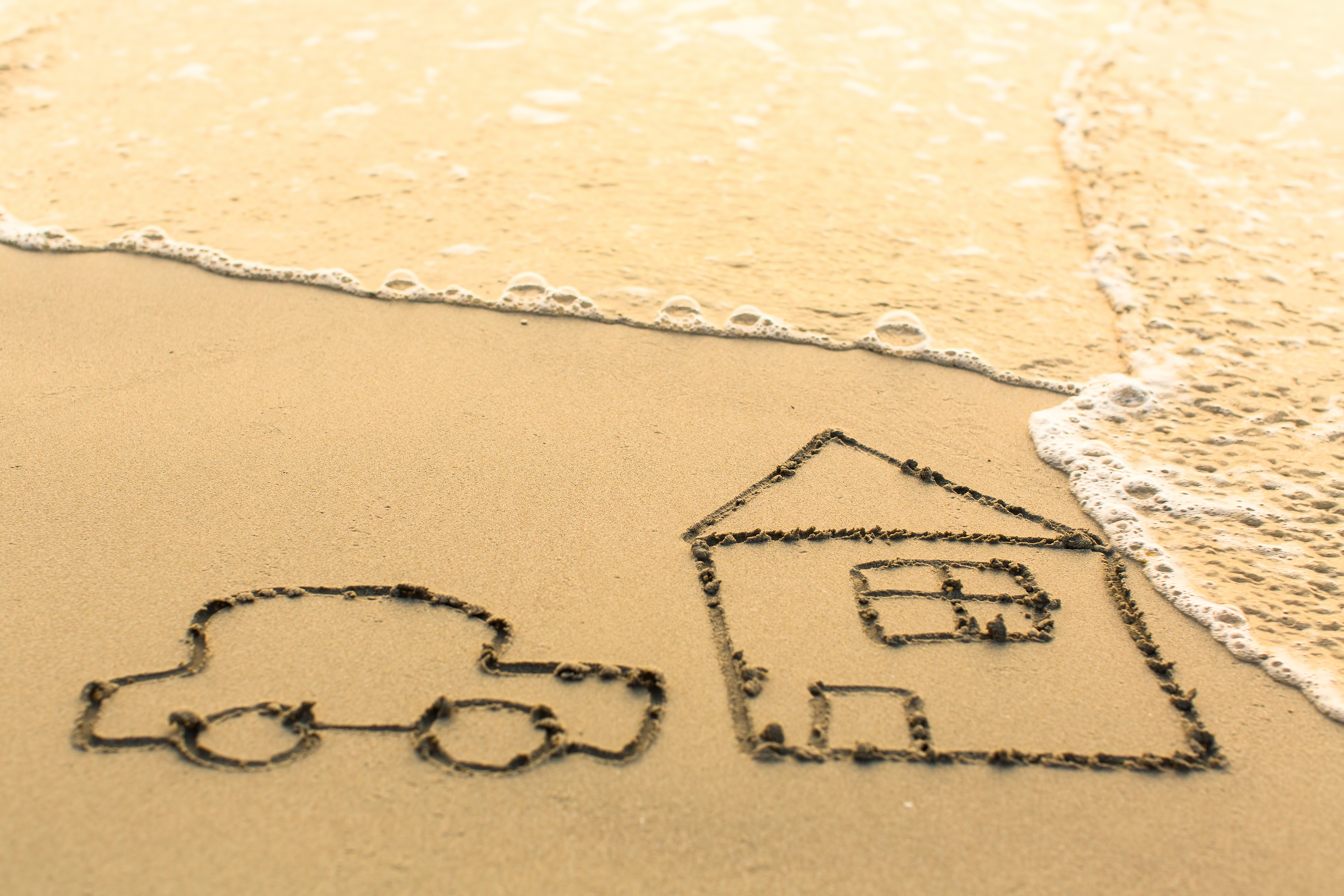 House and a Car drawing on the beach sand with the soft wave.