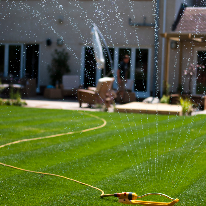 A photograph of a sprinkler watering a newly laid lawn