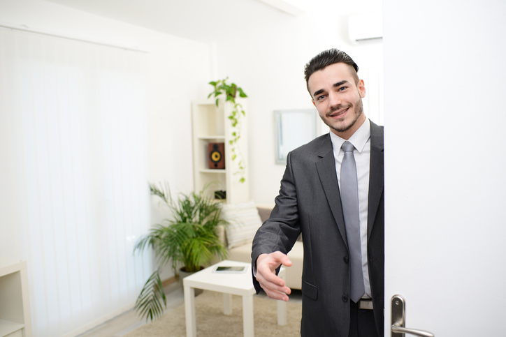 young businessman at the doorway giving hand to customer