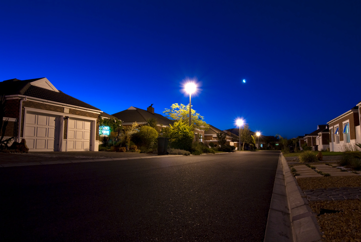 Urban night scene showing a road and various houses in a clear sky