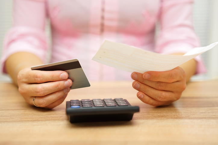 woman is holding bill and credit card in hands and calculating the costs